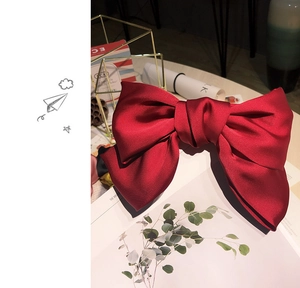 Close-up of a large oversized burgundy satin bow hair clip with a silky finish
