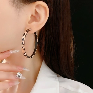 Gros plan de boucles d'oreilles créoles léopard sur un modèle sur fond noir