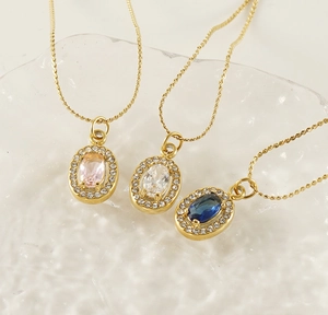 Close-up of gold titanium necklaces with pink, white, and blue oval zircon pendants