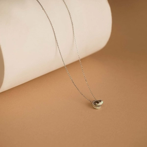 Detail of silver interlocking ring necklace featuring a white opal inlay on a pedestal