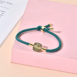 Détail du bracelet réglable en cordon tressé vert avec fermoir doré et pendentif pierre
