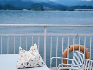 Detail of floral printed canvas tote bag on a lakeside table with scenic background