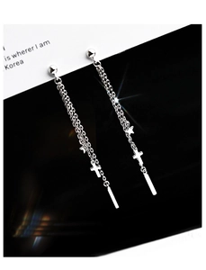 Detailed view of silver tassel earrings with cross and star charms on long chain links
