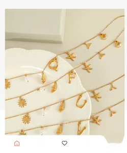 Detail of 18K gold plated steel chains with alphabet, seashell and starfish charms