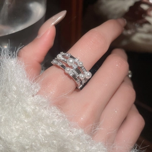 Macro shot of an elegant three-layer silver ring with white pearls and sparkling zircons