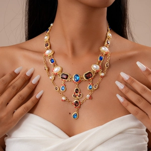 Close-up of layered vintage necklace with teardrop pearls and colorful gemstones on a model