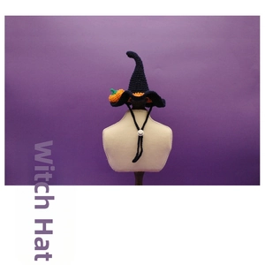 Dettaglio cappello da strega all'uncinetto per animali con zucca arancione su sfondo viola