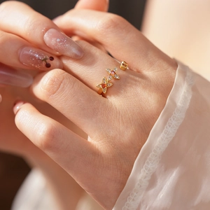 Makroaufnahme eines goldenen Blumenrings mit orangefarbenen Steinen und kleinen Diamanten