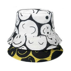 Folded cotton bucket hats in white and yellow featuring black graffiti smile patterns