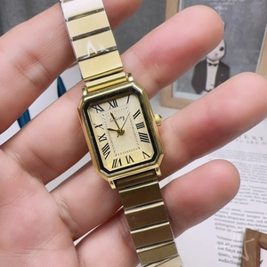 Close-up of a gold rectangular women watch with Roman numeral dial and metal strap
