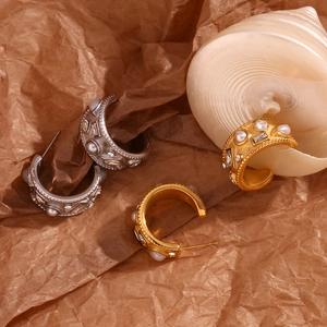 C-shaped 18K gold and silver plated earrings with pearls and crystals on brown paper