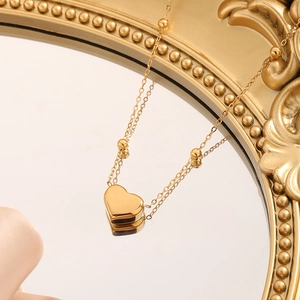 Elegant gold heart necklace with bead chain shown on a vintage mirror reflection