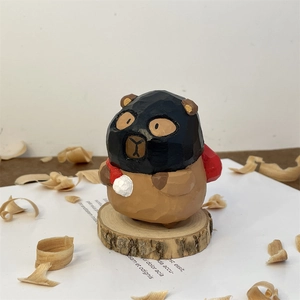 Detail showing hand-carved wooden bear figurine wearing a black ski mask and backpack