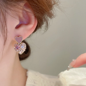 Elegant gold plated double heart stud earrings with sparkling pink crystals on a model