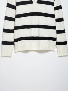 Close-up of black and white striped knit sweater showing ribbed V-neck and soft texture