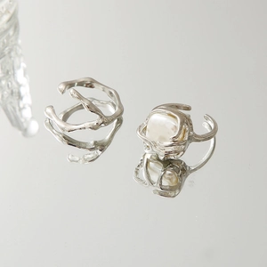 Detail view of silver heart-shaped ring set with pearls on a reflective mirror surface