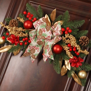 Christmas pine cone and red berry lintel swag decoration hanging on a wooden door