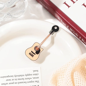 Detailed view of a guitar-shaped acrylic hair clip on a decorative white display plate