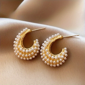 Elegant gold C-shaped hoop earrings with faux pearl embellishments on silk background