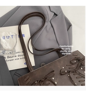 Detail of dark brown leather shoulder bag featuring silver rivets and bow tie laces