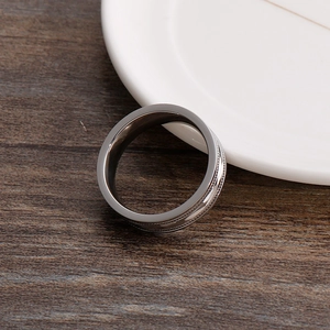Close-up of silver titanium steel ring with intricate engraved hollow groove patterns