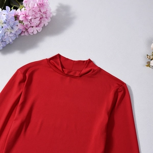 Detail of red mock neck long sleeve top with textured stretchy fabric on grey background