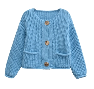 Detail of blue chunky knit cardigan featuring gold buttons and dual front pockets