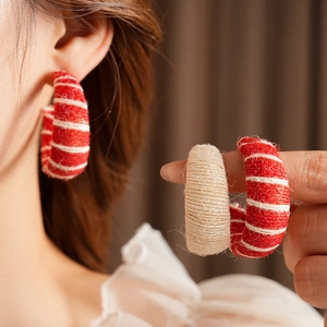 Detailed close-up of C-shaped hoop earrings featuring woven fabric and knit texture