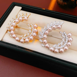 Macro detail of gold and silver brooches with pink pearls and cubic zirconia on velvet