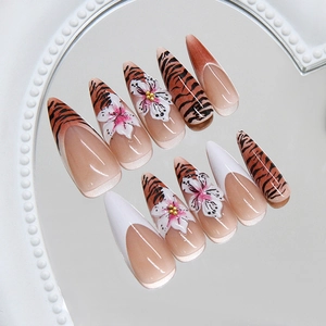 Press-on nails featuring zebra stripes and 3D floral accents on heart mirror display