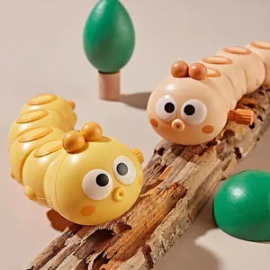 Wind-up crawling caterpillar toys in yellow and beige colors on wooden surface