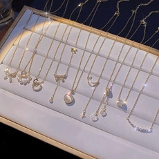 Close-up of gold titanium steel necklaces with pearl and butterfly pendants on a tray