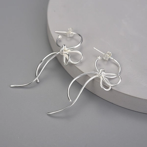 Minimalist S925 sterling silver bow ribbon stud earrings for women on a geometric background