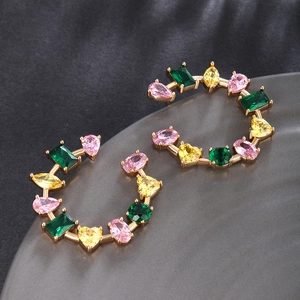 Macro detail of gold earrings featuring vibrant pink, yellow, and green zircon gemstones