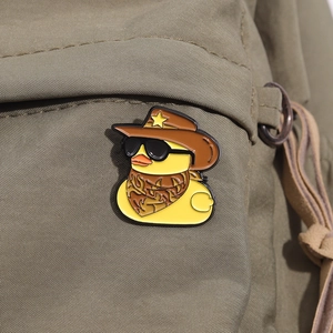 Détail du pin's canard cool en émail avec chapeau de cowboy sur sac en toile verte