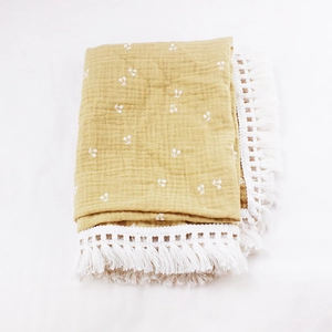 Detail of ginger cotton baby blanket with white cherry prints and elegant crochet tassels