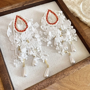 Detail of bohemian lace floral earrings with red rhinestones and white teardrop pearls