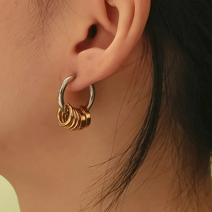 Detailed macro view of two-tone stainless steel hoop earrings with gold ring charms