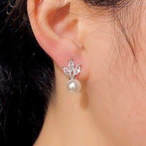 Macro shot of elegant marquise zirconia stud earrings with white pearl drop on model