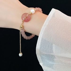 Close-up of pink strawberry quartz beaded bracelet with white pearl on woman's wrist