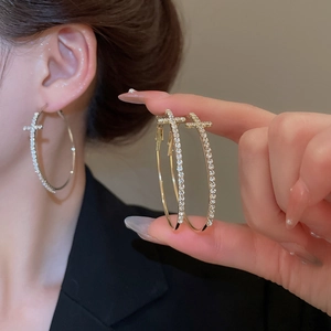 Vue détaillée de créoles dorées et argentées avec pendentifs croix en diamants