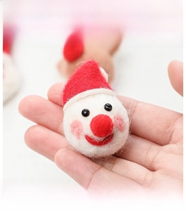 Close-up of handmade wool felt Santa Claus ornament held in hand for Christmas decor