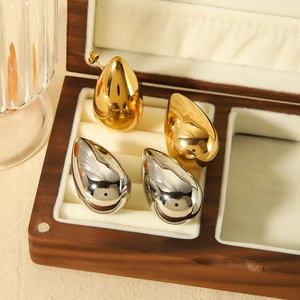 Polished gold and silver teardrop earrings displayed in a luxury wooden jewelry box