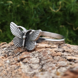 Detailed view of vintage silver butterfly ring placed on natural wood bark background