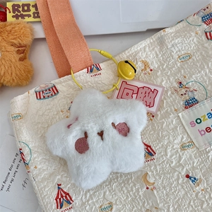 Close-up of white plush star keychain with embroidery on a cream canvas tote bag