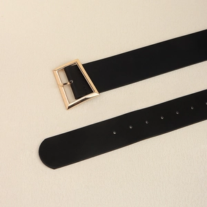 Detail of black wide waist belt with golden geometric buckle and adjustment holes