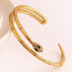 Close-up of gold snake bracelet featuring green gem eyes and sparkling white zircon detail