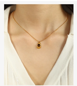 Model wearing gold necklace with irregular water drop pendant and brown tiger eye stone