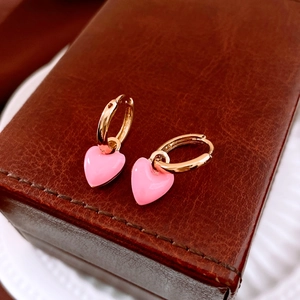 Detail of pink enamel heart earrings on a brown leather jewelry box corner