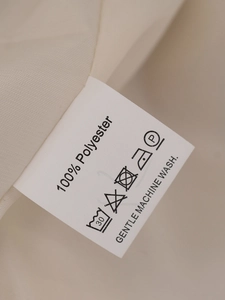 Gros plan de l'étiquette d'entretien du manteau en fausse fourrure indiquant 100% polyester